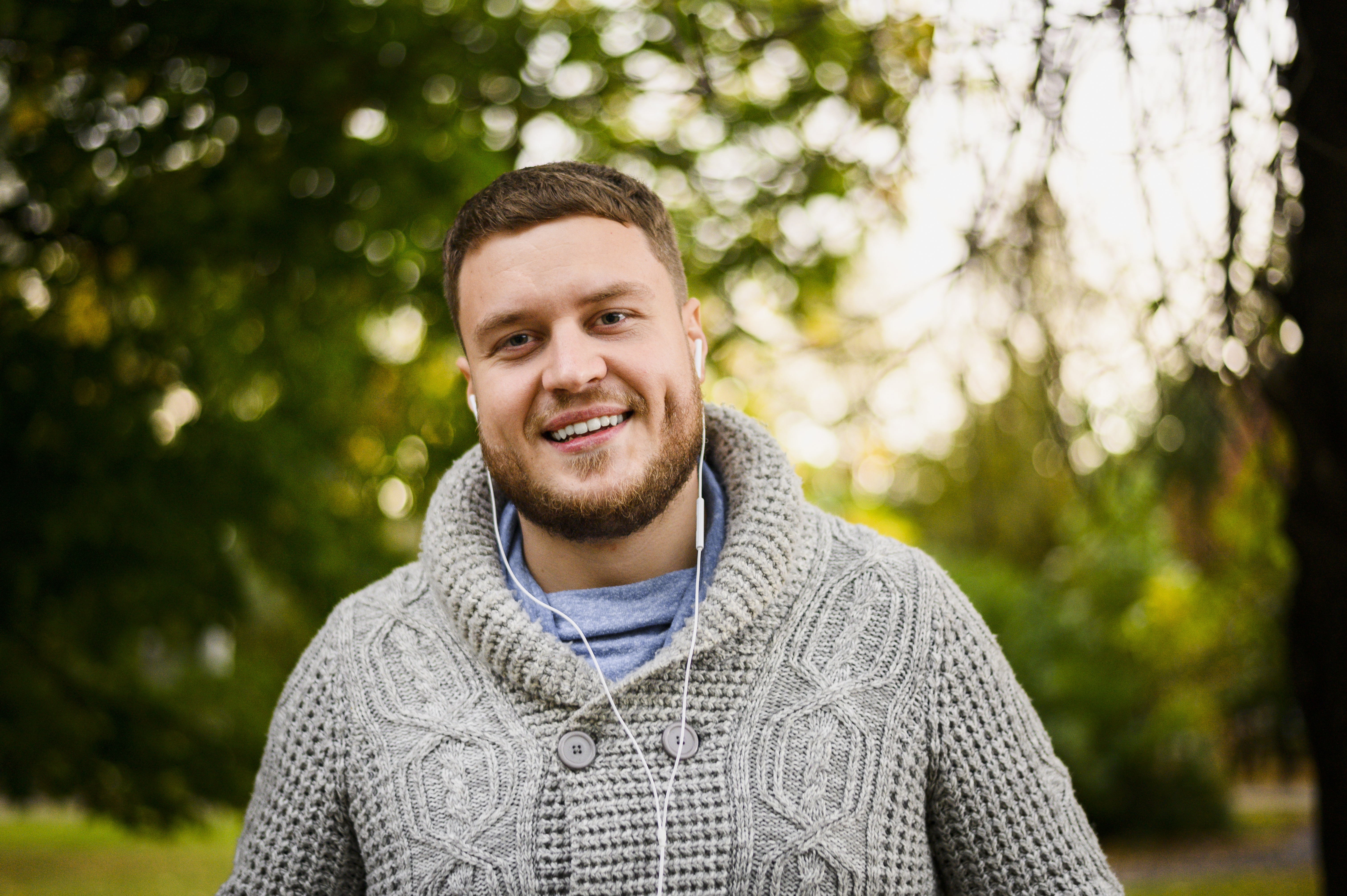 Lächelnder Mann mit Kopfhörern im Park