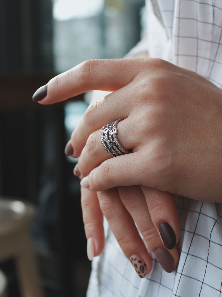 Hände mit einem Ring, der einen Stern hat, mit braunen Nägeln. jewelry