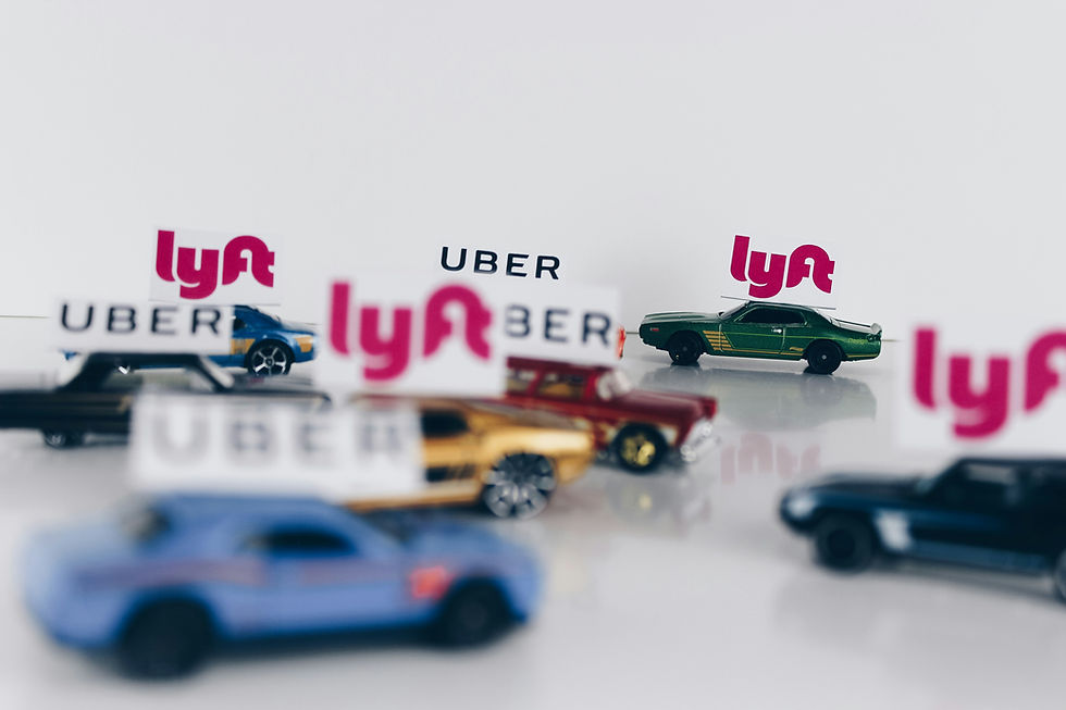Toy cars on a white background, each displaying Uber and Lyft logos, illustrating rideshare vehicles.