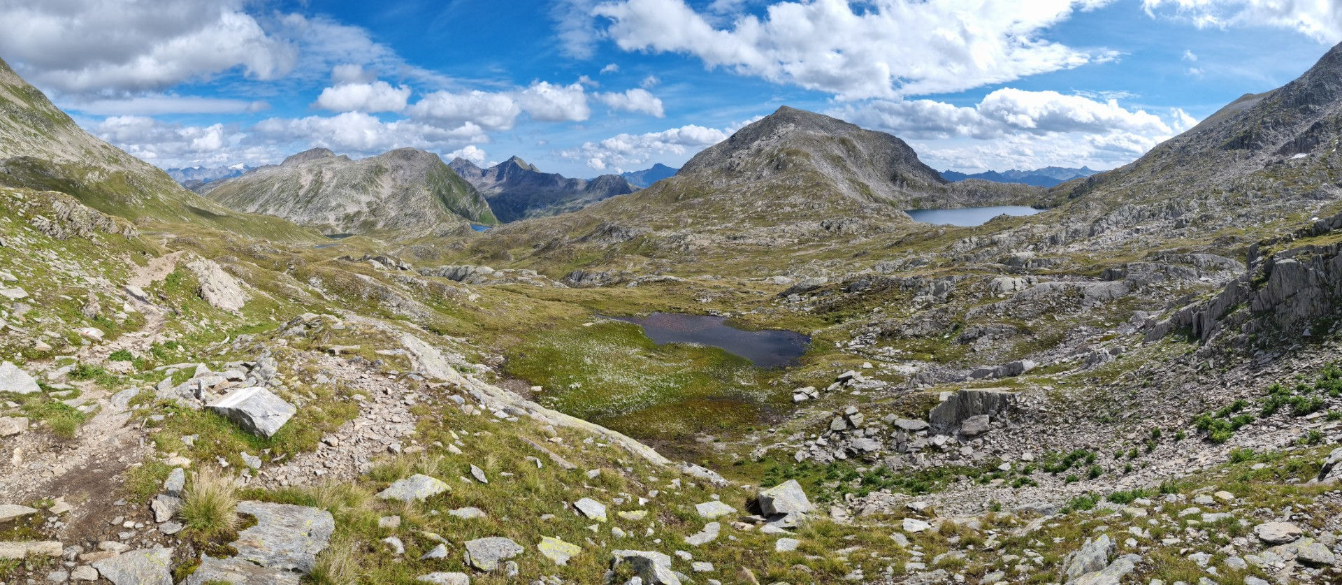 Weites Panorama des Val Cadlimo mit mehreren Bergseen, Wanderweg und Gotthard-Bergkette
