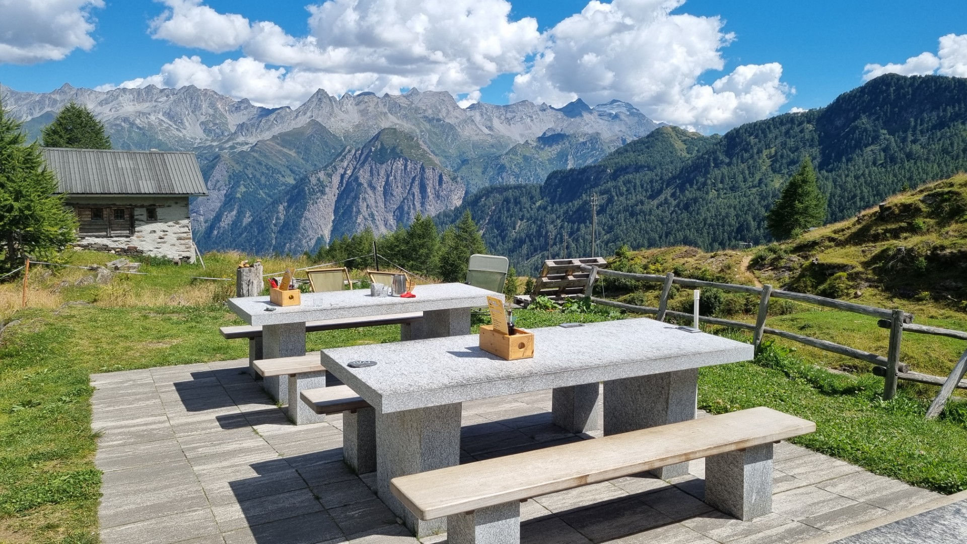 Granitsteintische auf der Terrasse der Bovarinahütte mit weitem Bergpanorama Richtung Surselva