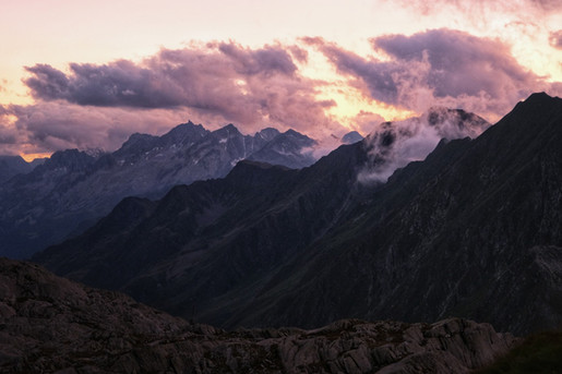 Abendrot über mehreren Bergketten im Val Cadlimo mit violett-rosafarbenem Himmel