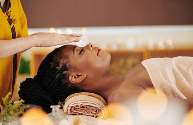 client-on-massage-table-receiving-reiki-healing-service-with-practioners-hands-over-clients-head