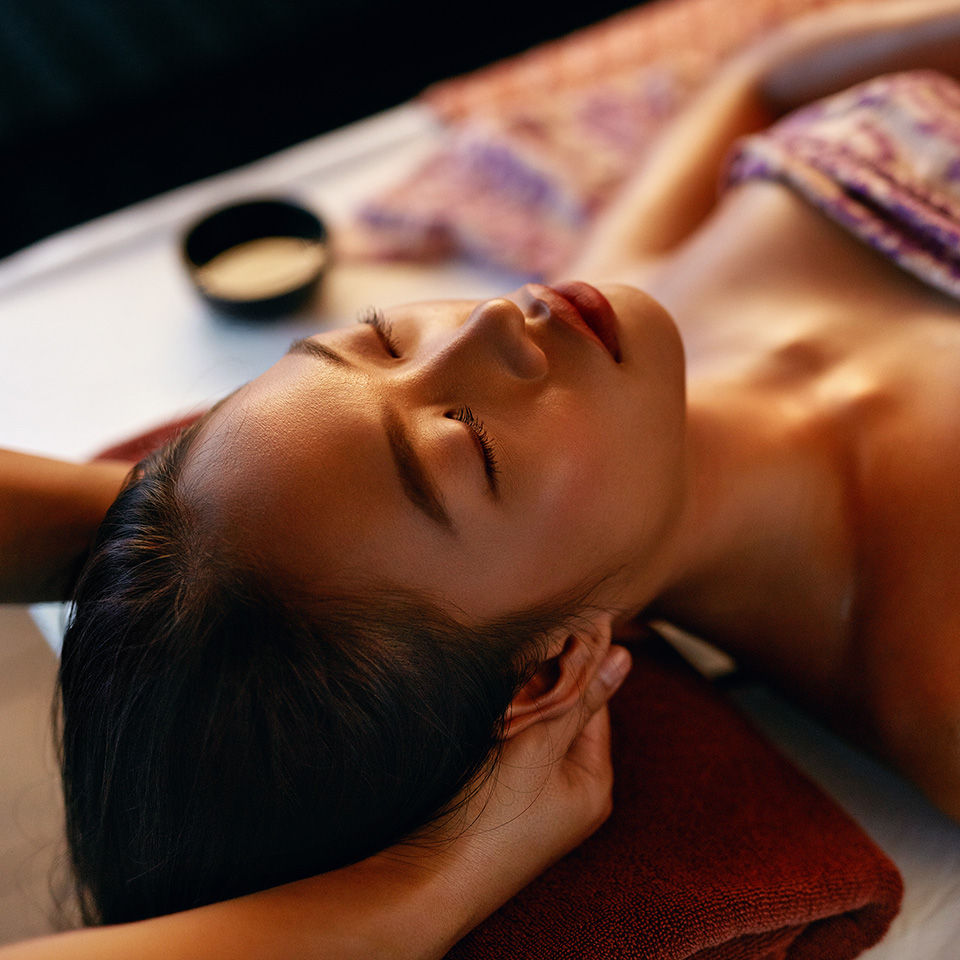 a-woman-lying-down-receiving-a-relaxing-head-massage