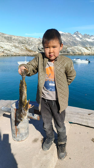 enfant inuit avec le poisson qu'il vient de pêcher