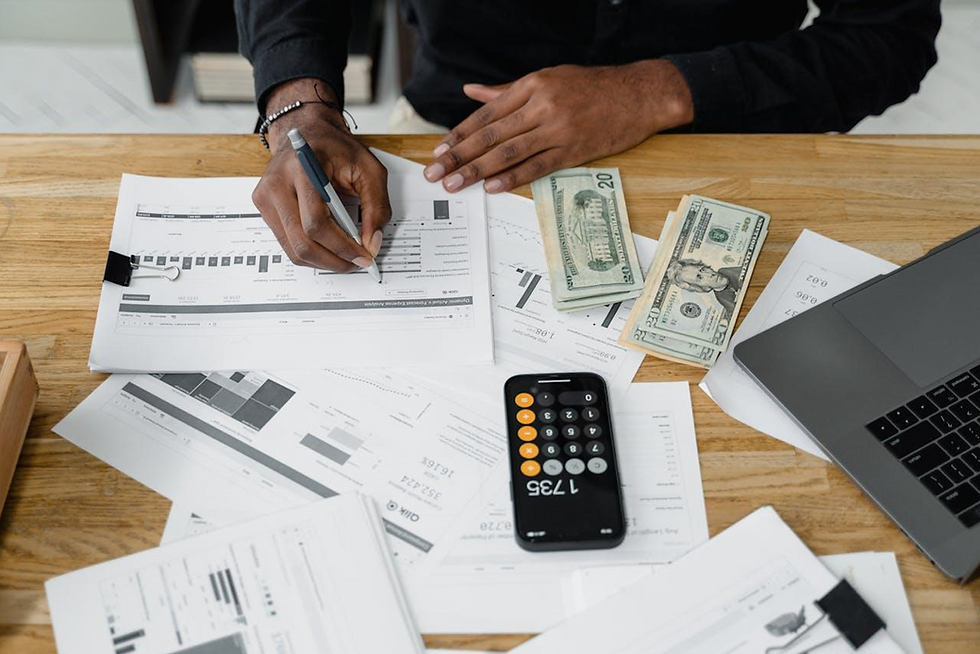 A person working at their desk with papers, calculator, and money.
