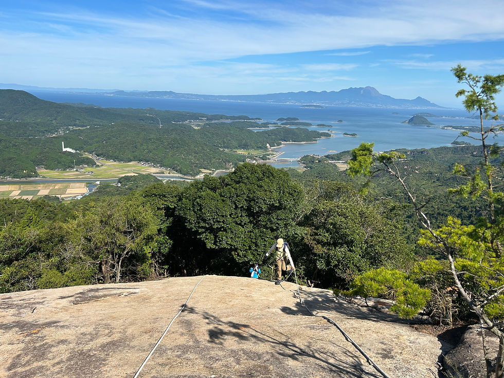 大岩を登る。後方の海の向こうに雲仙普賢岳