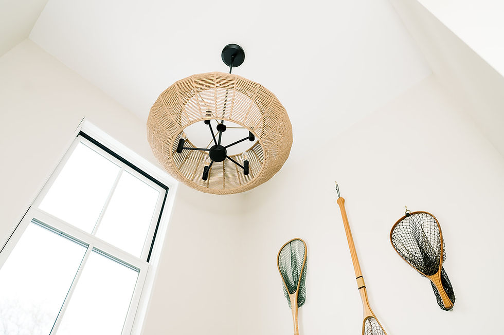 A unique coastal-inspired ceiling light fixture with a woven rattan shade, accompanied by decorative wooden fishing nets mounted on the wall, adding rustic charm.