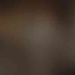 Suave man in tailored brown suit poses in opulent setting.