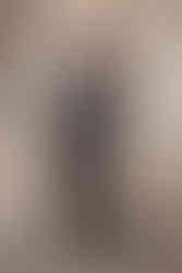 Fashionable woman in black patent leather outfit posing confidently outdoors.