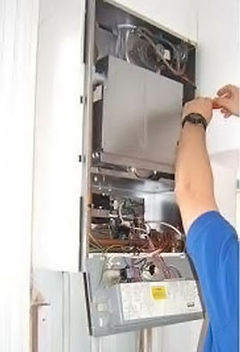 Image shows a man in a blue shirt fixing a boiler.