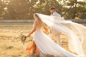 Bride and Groom walking in the fields at sunset