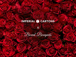 Red roses fill the image with text "IMPERIAL CARTONS x Boxed Bouquets" in the center. Lush, romantic setting with vibrant color.
