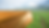 Cracked, dry earth with a narrow water stream leads to lush green grass, set against misty hills and a cloudy sky. Mood: contrasting.