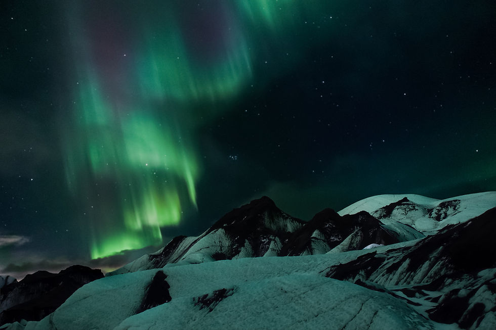 Northern lights in vibrant green illuminate a starry sky above snowy mountains, creating a serene and mystical night scene.