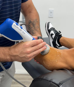 Patient receiving shockwave therapy treatment on their leg, highlighting a non-invasive method for pain relief and tissue healing.