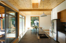 Cuisine avec comptoir en pierre naturelle. frigo en inox. plafond en bois avec poutre apparente.
grande fenêtre. design intérieur lumineux.