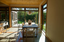 salle à manger avec vue sur jardin. baie vitrée. plafond en bois. Lampe suspendue design.