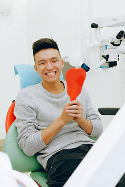 Patient checking his teeth in the mirror after dental cleaning