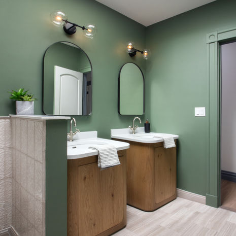 Bathroom remodel in Somerville MA with green walls, wood vanity, double mirrors, and modern lighting by Morse Constructions