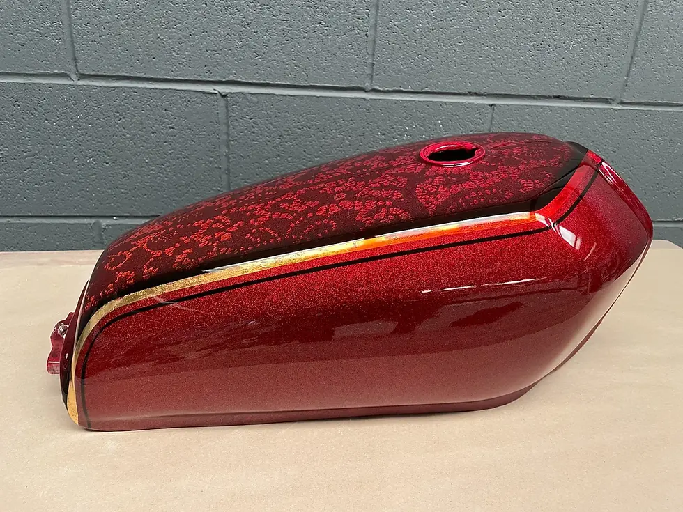 Custom motorcycle tank with hand-carved lace pattern and crimson candy paint finish