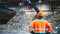 waste site operator looking at piles of waste in warehouse