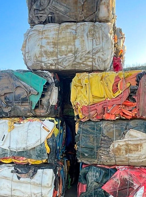 baled rigid plastics stacked neatly in sunshine about to be organised for transport
