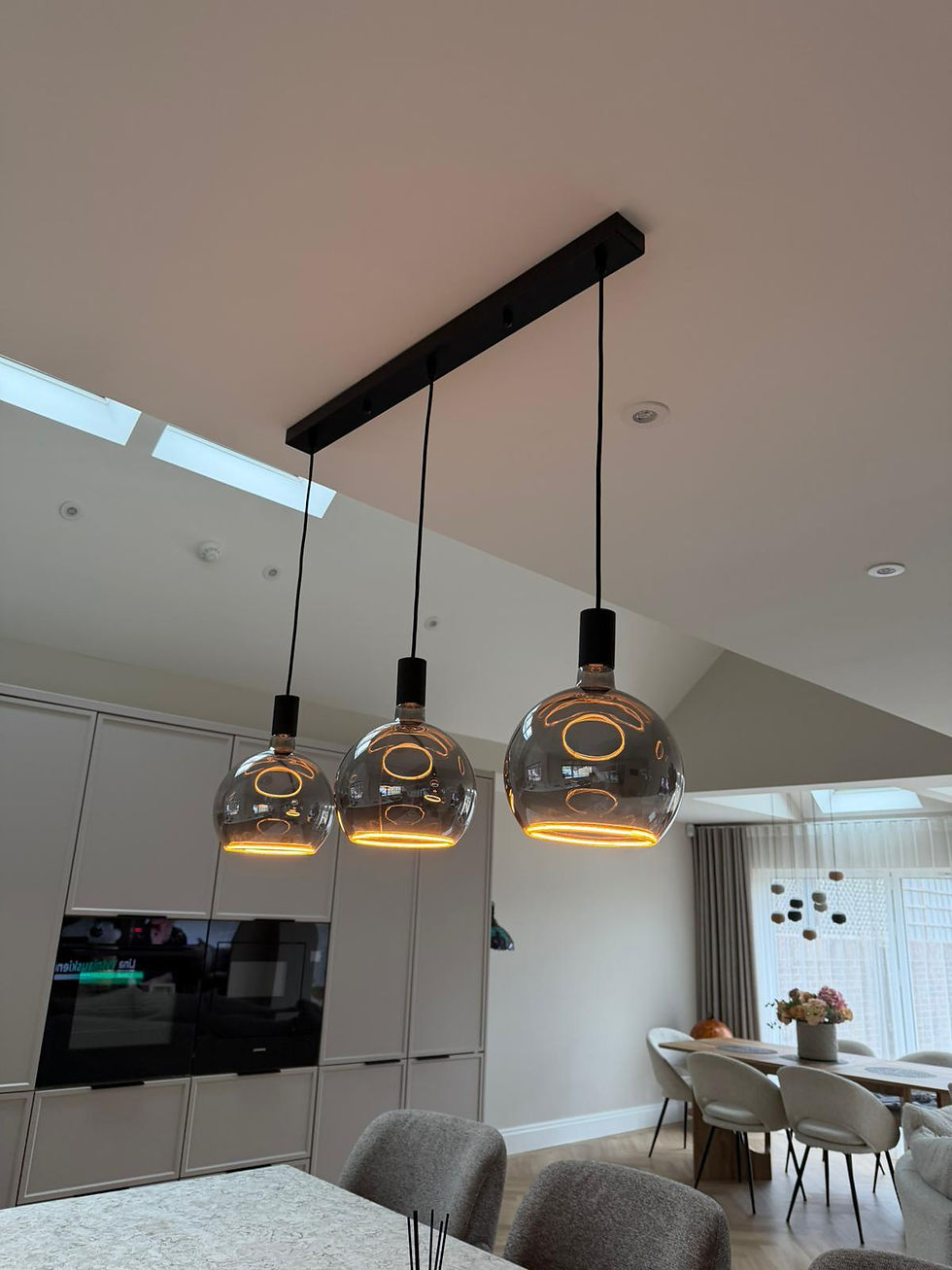 Three amber glass globe pendant lights hung over a kitchen island, Surrey