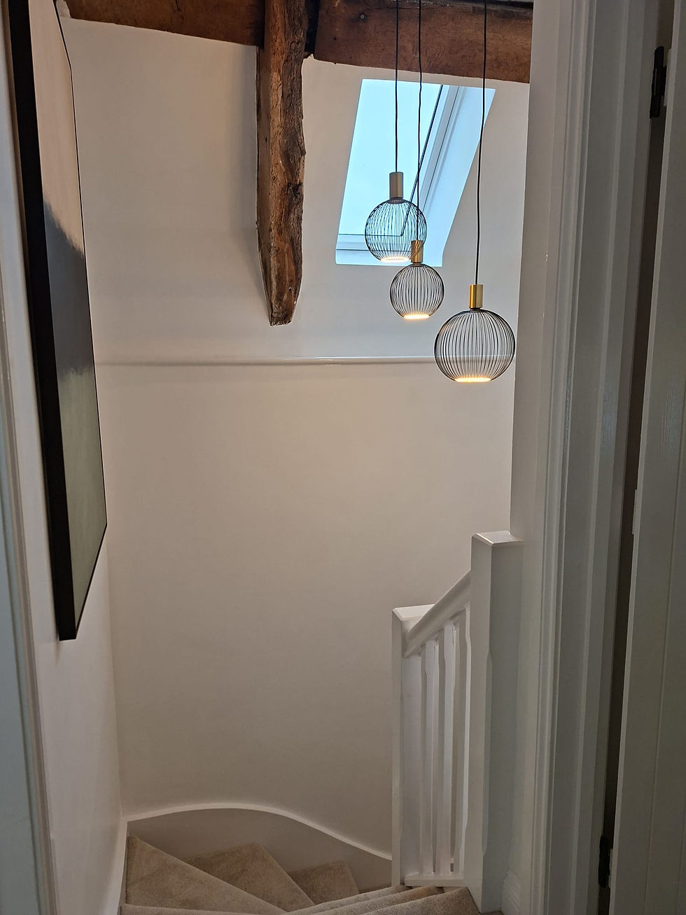 Three wire-cage globe pendant lights hung under a skylight on a landing, Surrey home