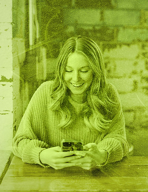 A woman smiling while managing small business social media on her smartphone.