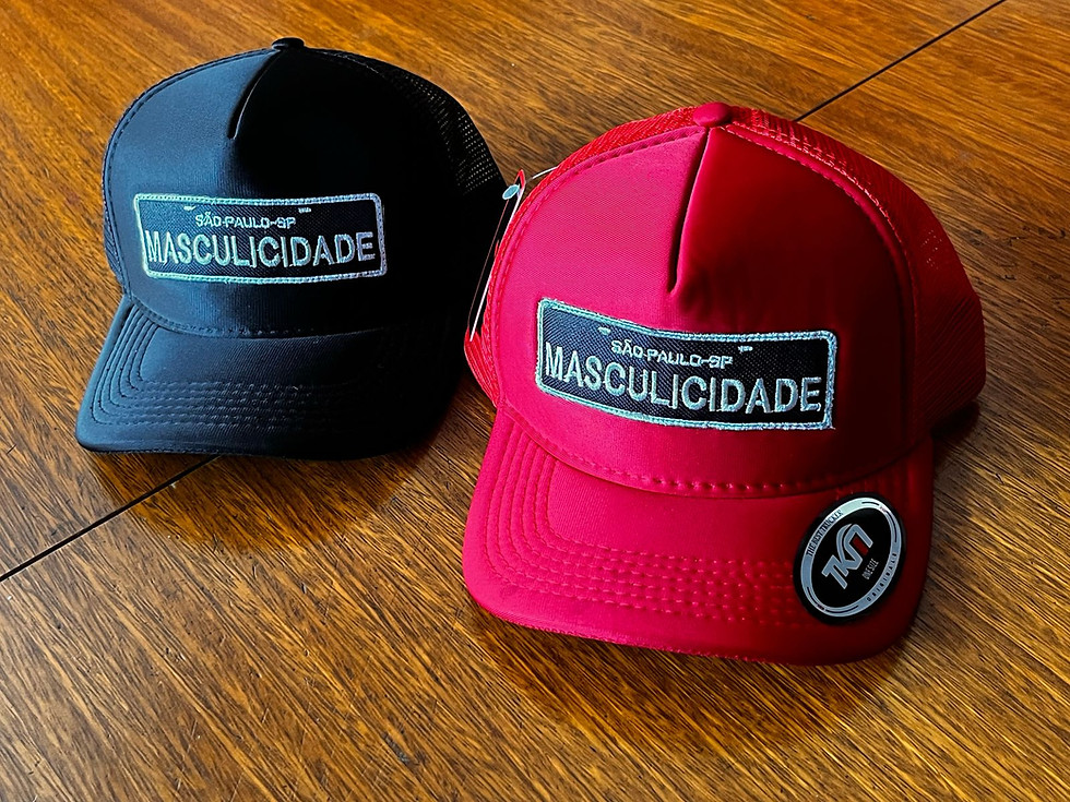 2 bonés Masculicidade em cima da mesa. Um preto e um vermelho.