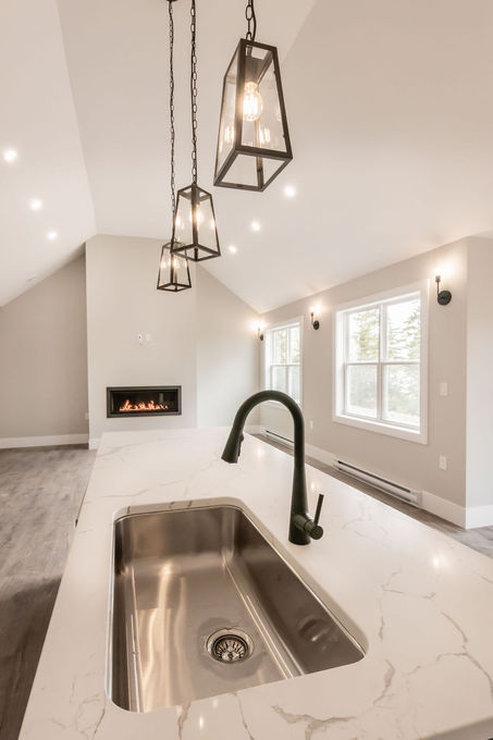Kitchen interior with view of fireplace in the Petpeswick Bungalow built by JonesCo Builders