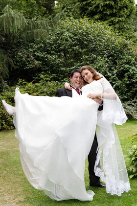 Groom lifting his bride in a flowing wedding gown in a garden