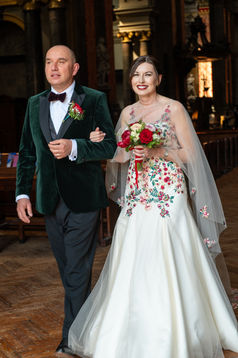 Bride with bold red lip bridal makeup and a floral embroidered gown walking down the aisle