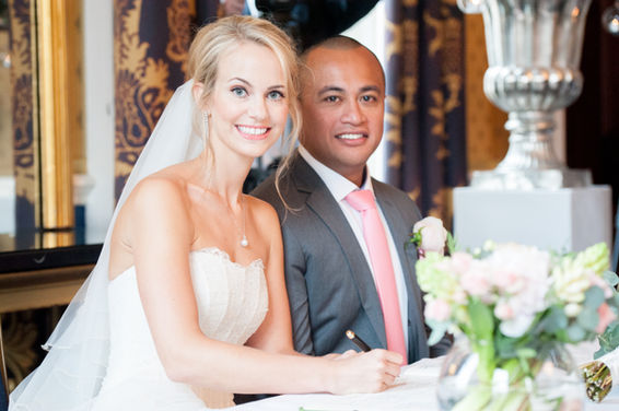 Blonde bride with a veil and fresh wedding day makeup signing the register with her groom