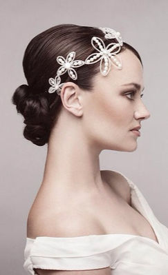 Low bridal bun with a crystal flower hair accessory and soft bridal makeup