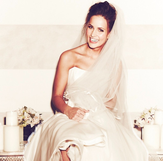 Laughing bride with soft glowing makeup and a loose updo under a long veil