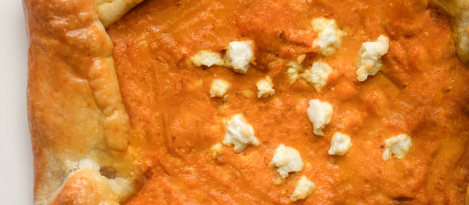 Rustic sourdough pumpkin feta galette with a golden flaky crust, creamy pumpkin filling, and crumbled feta on a neutral background.