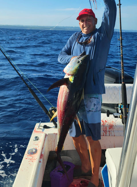 Fisherman proudly displays a large tuna catch.