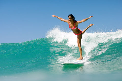 Woman gracefully balances on surfboard, arms outstretched
