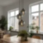 Close-up of three glass pendant lights hanging above a wooden dining table with indoor plants and natural daylight.