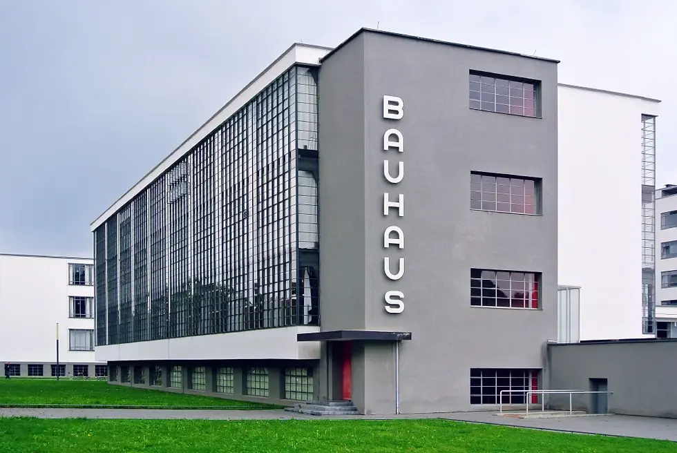 The Bauhaus building in Dessau, Germany, a modernist complex with glass curtain walls and cantilevered structures illuminated from inside.
