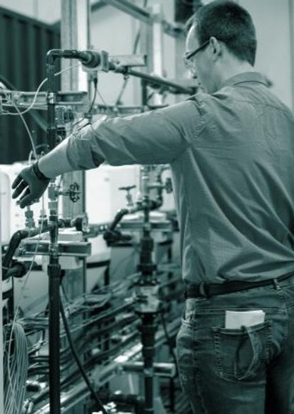 Engineer manually turning valves and operating process equipment.