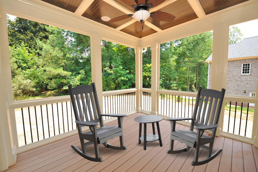 Polymer rocking chairs and end table on a covered porch.