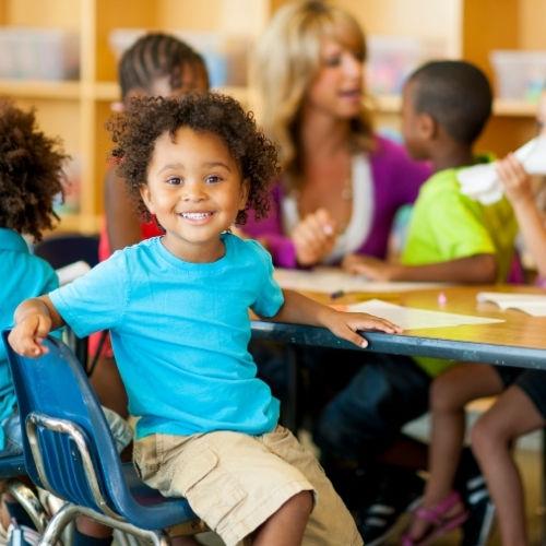 Pre-K boy smiling at his desk