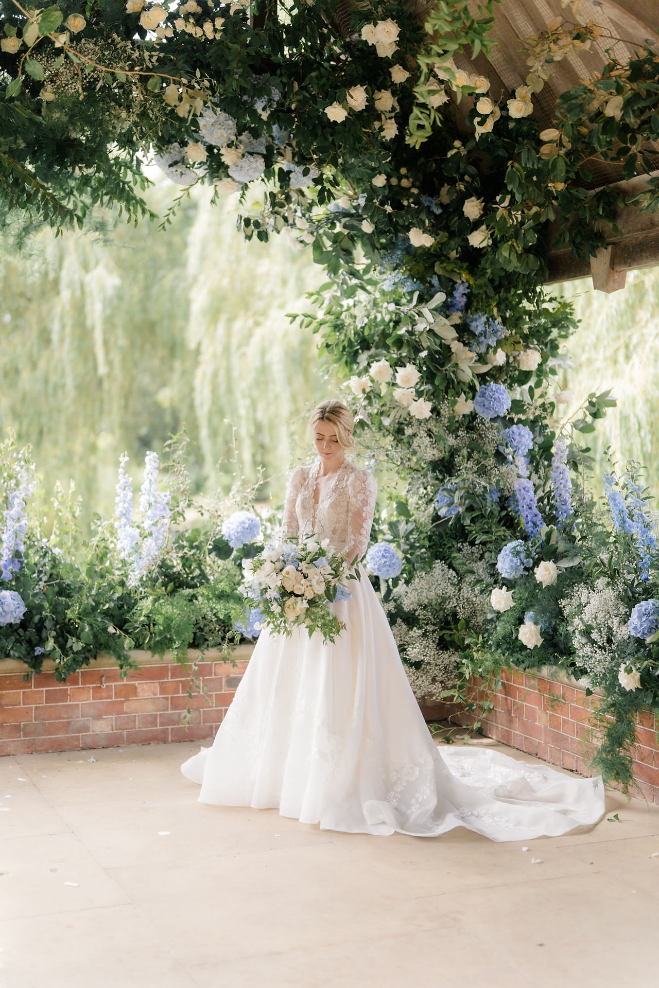 waddesdon manor wedding photographer captures bride looking at her bouquet in front of flowers 