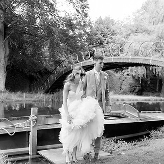 Bride and groom walking off boat t Avington House