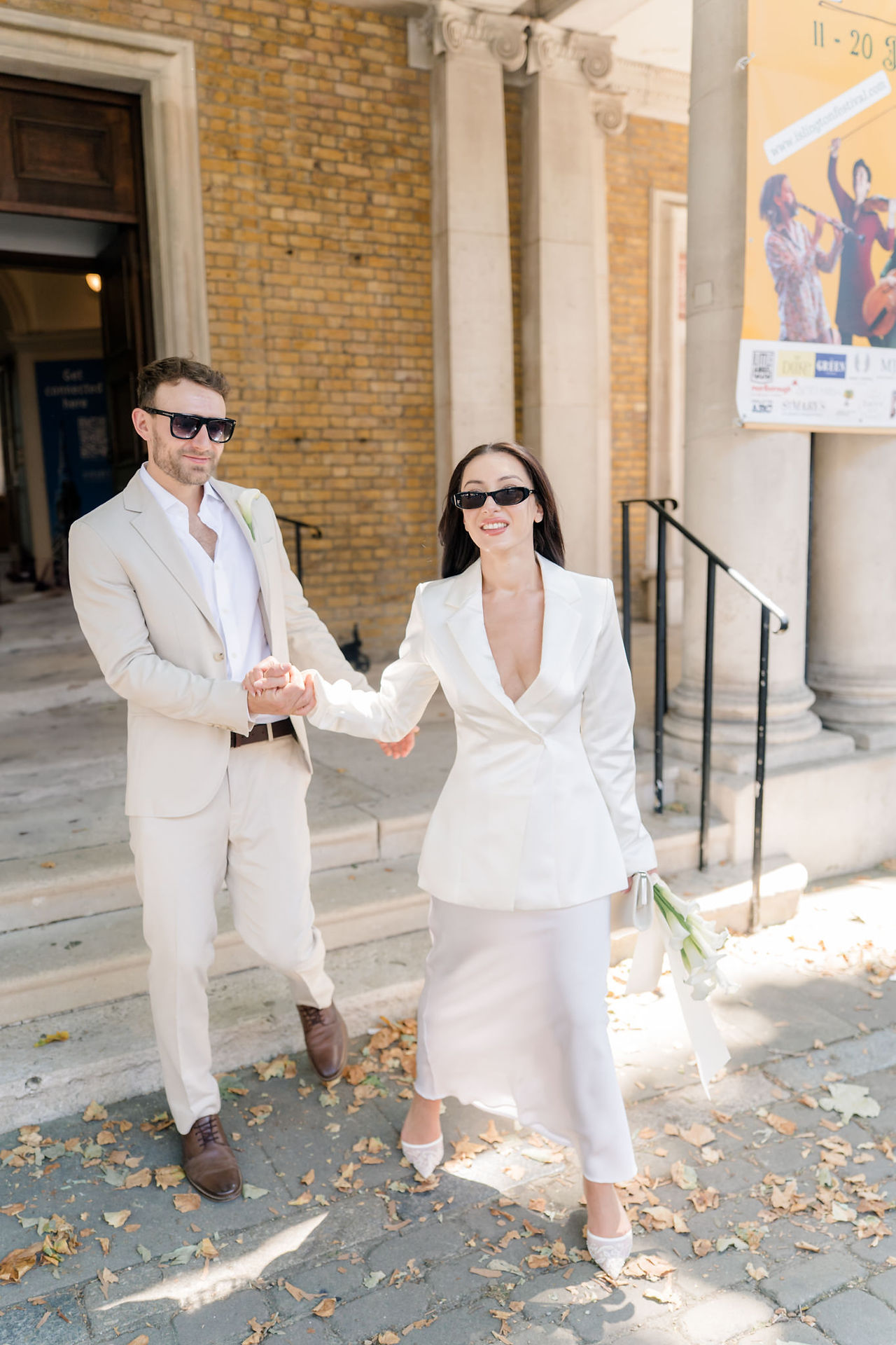 Islington town hall wedding with groom holding hands with bride while taking sunglasses off
