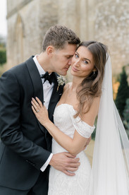 Groom kissing side of brides face outside Ivy lodge wedding