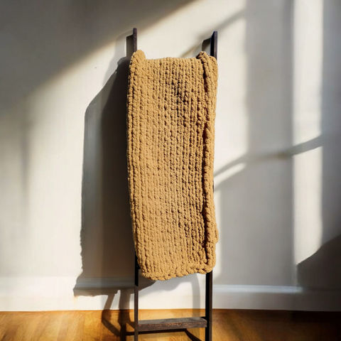 Chunky knit blanket on a wooden blanket ladder
